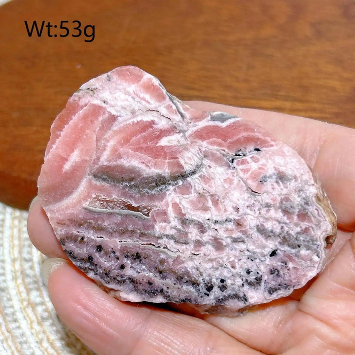 Polished Rhodochrosite raw slab featuring rose-pink banding and natural edges for heart chakra healing and display.
