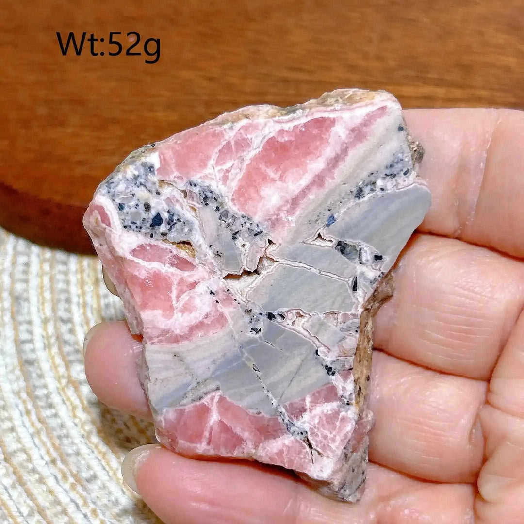 Polished Rhodochrosite raw slab featuring raspberry pink banding and natural edges for heart chakra healing and display.