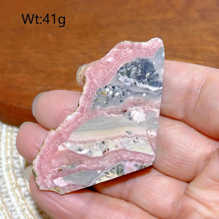 Polished Rhodochrosite raw slab featuring rose-pink banding and natural edges for heart chakra healing and display.