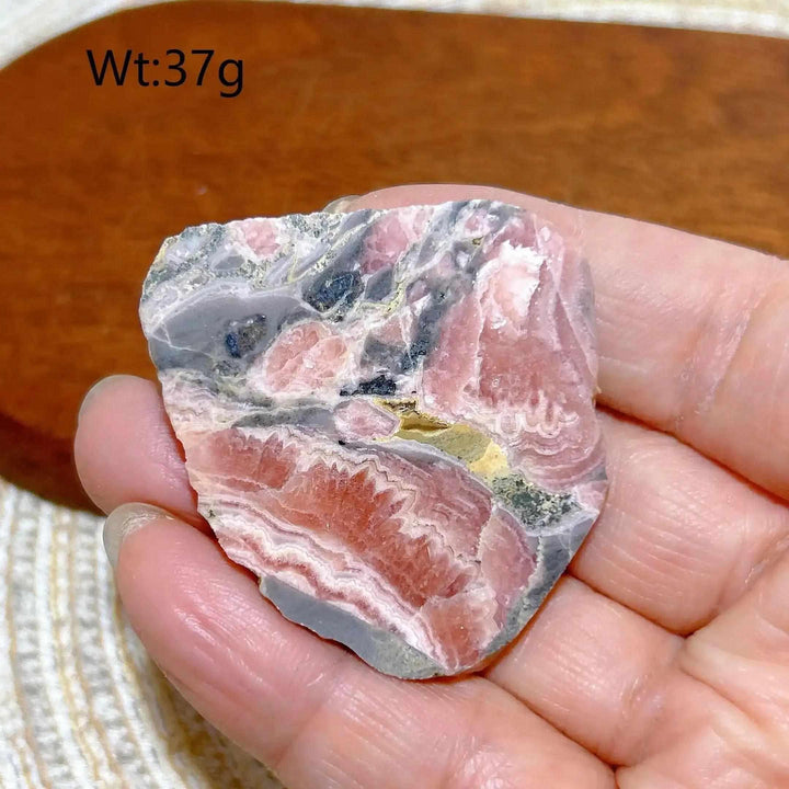 Polished Rhodochrosite raw slab featuring raspberry pink banding for heart chakra healing and self-love.