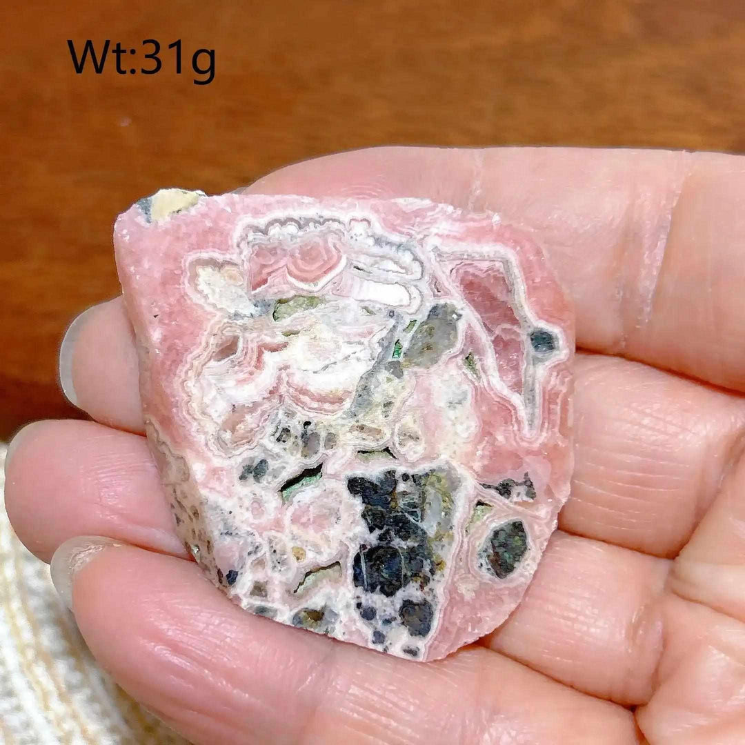 Polished Rhodochrosite raw slab featuring rose-pink banding and natural edges for heart chakra healing and display.