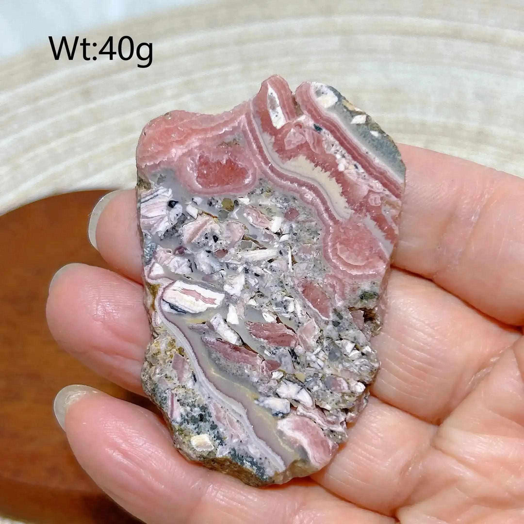 Polished Rhodochrosite raw slab featuring raspberry pink banding and natural textures for heart chakra healing and display.