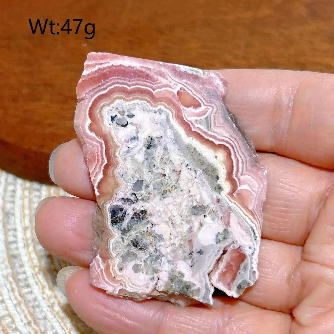 Polished Rhodochrosite raw slab featuring rose-pink banding and a crystalline center for heart chakra healing.