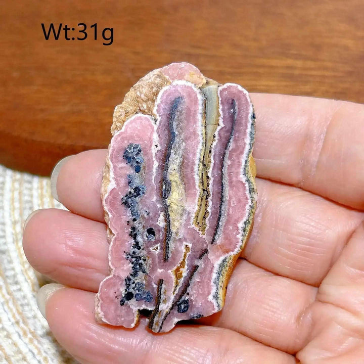 Polished Rhodochrosite raw slab featuring raspberry pink banding and natural edges for heart chakra healing and display.