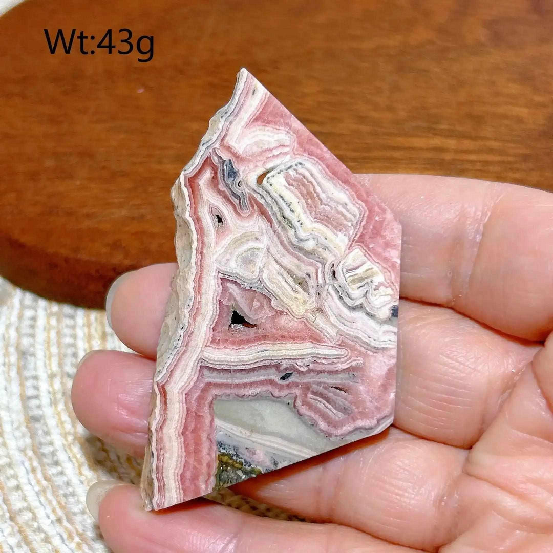 Polished Rhodochrosite raw slab featuring rose-pink banding and natural edges for heart chakra healing and display.