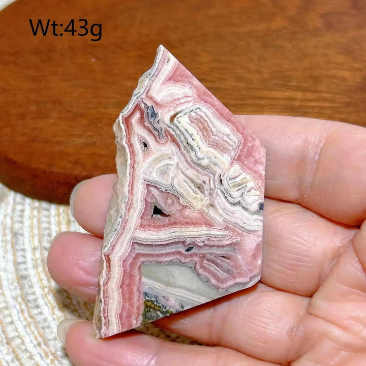 Polished Rhodochrosite raw slab featuring rose-pink banding and natural edges for heart chakra healing and display.