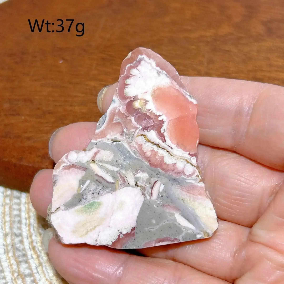 Polished Rhodochrosite raw slab featuring rose-pink banding and natural edges for heart chakra healing and display.