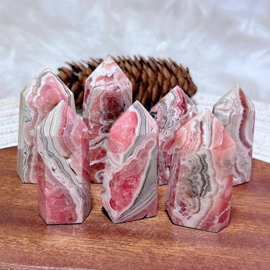 Polished Rhodochrosite tower points featuring vibrant rose pink and white banding for Heart Chakra healing and self-love.