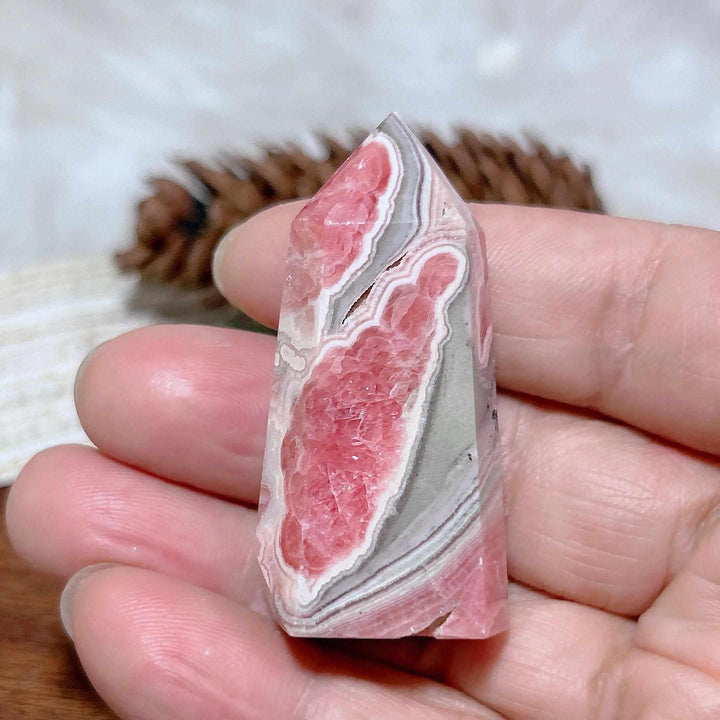 Polished Rhodochrosite tower point featuring vibrant rose-pink hues and soft white banding for heart chakra healing.
