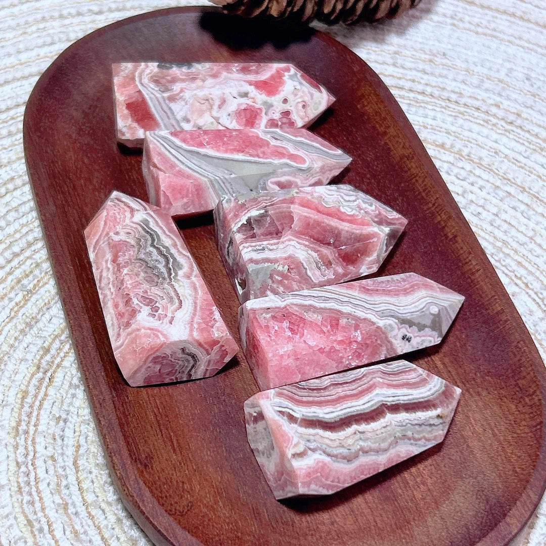 Polished Rhodochrosite tower points featuring raspberry pink hues and white banding for Heart Chakra healing and self-love.