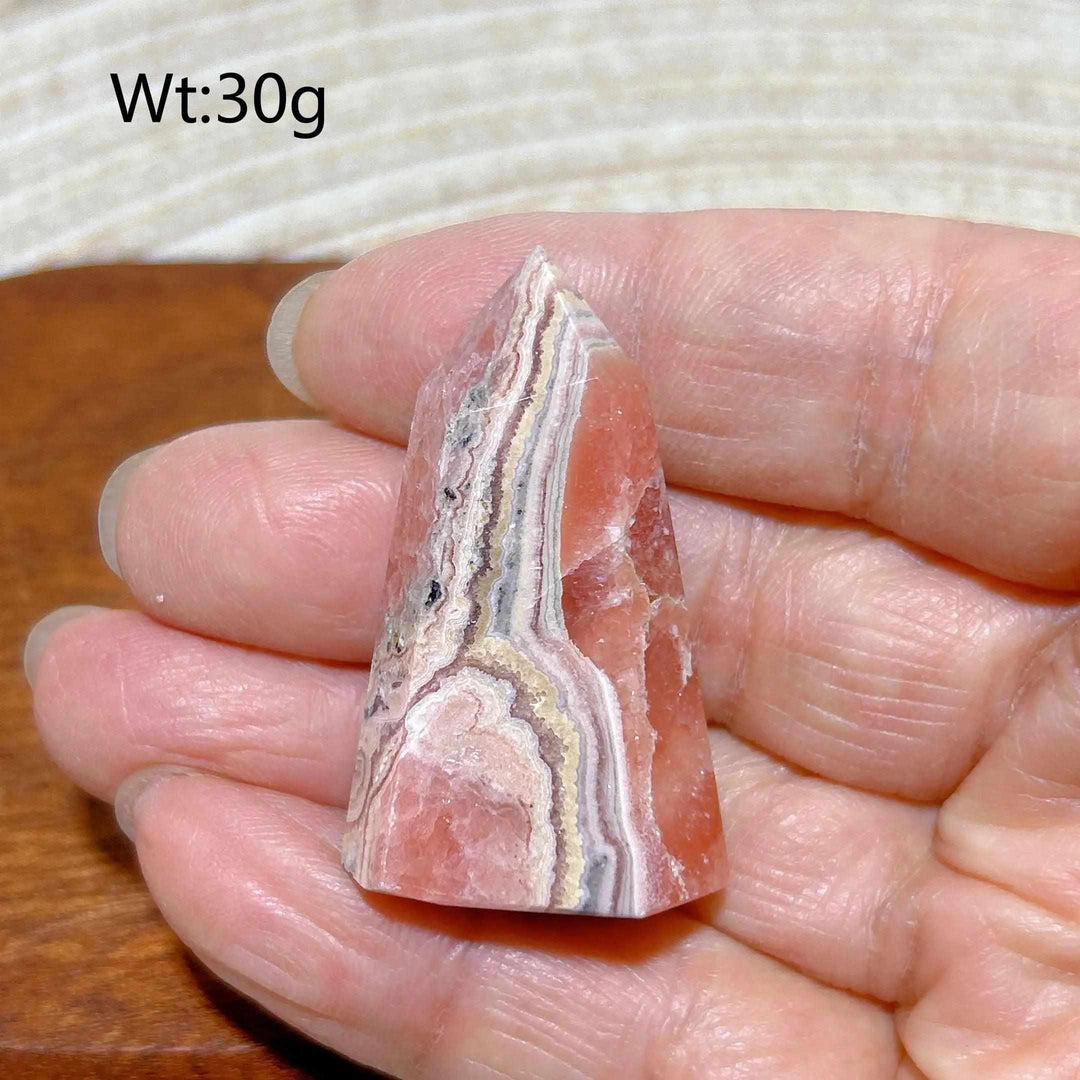 Polished 30g Rhodochrosite tower point featuring beautiful rose pink hues and intricate white banding for heart chakra healing.