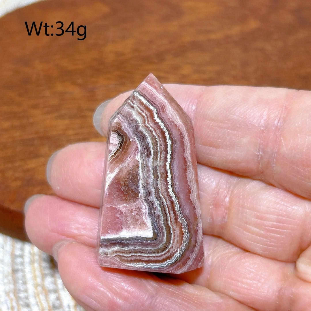 Polished 34g Rhodochrosite tower point featuring beautiful rose pink and white banding for heart chakra healing.