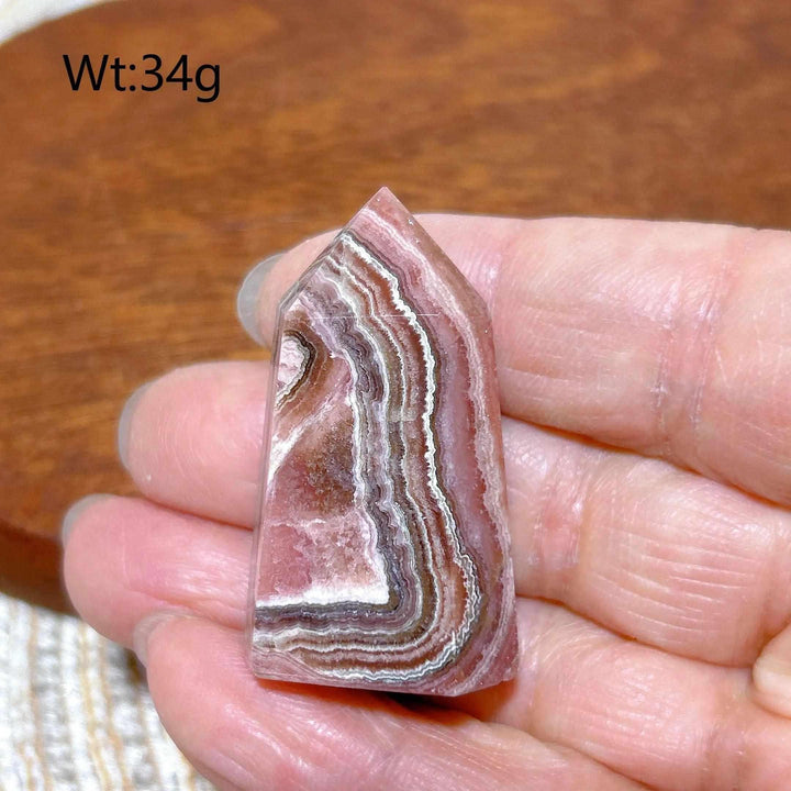 Polished 34g Rhodochrosite tower point featuring beautiful rose pink and white banding for heart chakra healing.