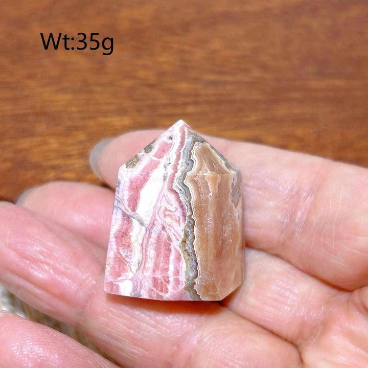 Polished Rhodochrosite tower point featuring beautiful rose pink and white banding for heart chakra healing.