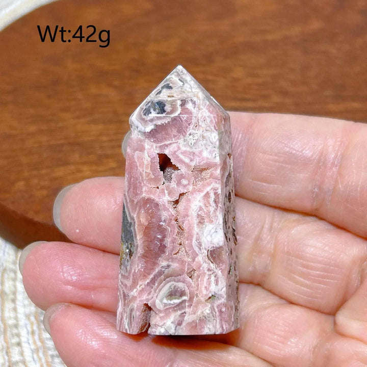 Polished 42g Rhodochrosite tower point featuring rose pink hues and white banding for heart chakra healing and self-love.
