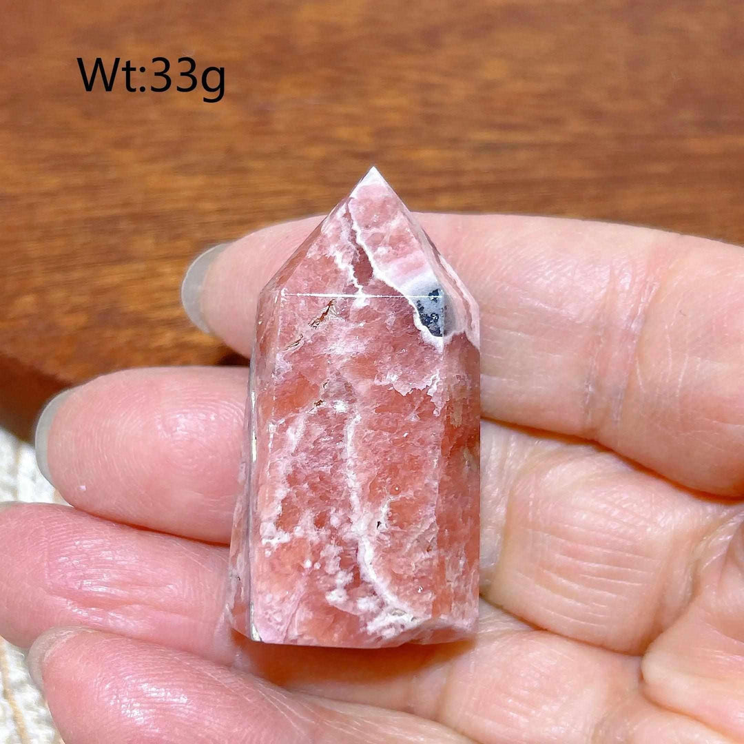 Polished 33g Rhodochrosite tower point featuring rose pink hues and white banding for heart chakra healing and self-love.
