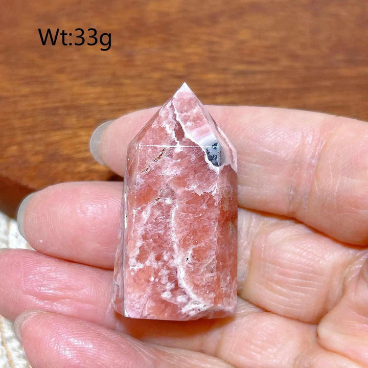 Polished 33g Rhodochrosite tower point featuring rose pink hues and white banding for heart chakra healing and self-love.