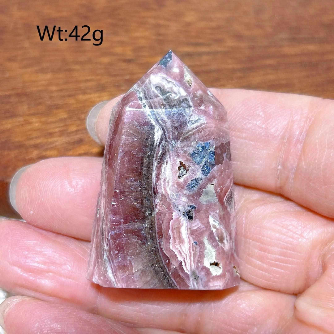 Polished 42g Rhodochrosite tower point featuring raspberry pink hues and white banding for heart chakra healing.