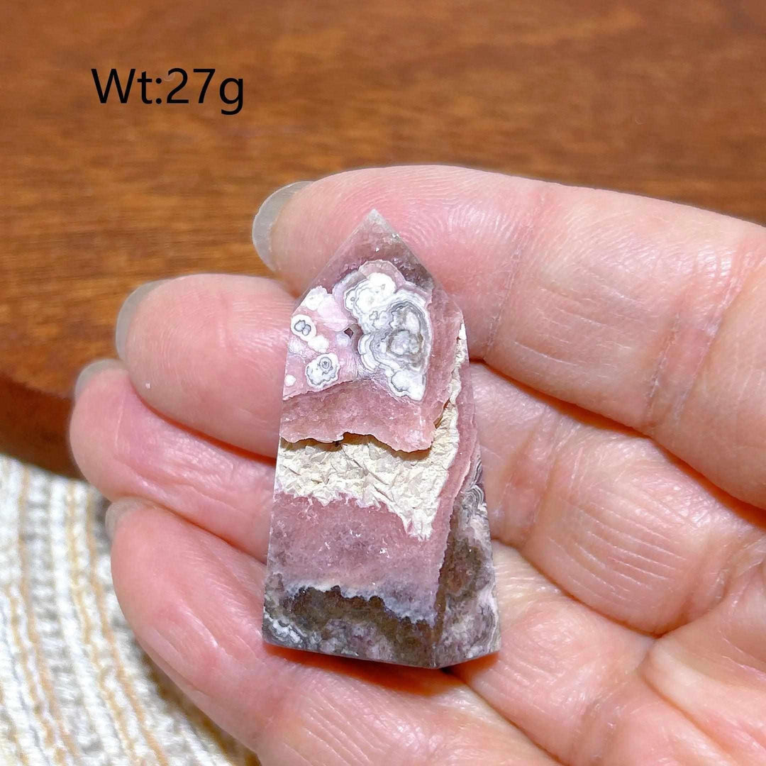 Polished Rhodochrosite tower point featuring raspberry pink hues and white banding for heart chakra healing.