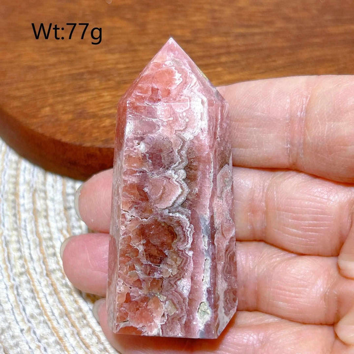 Polished Rhodochrosite tower point featuring raspberry pink hues and white banding for heart chakra healing.