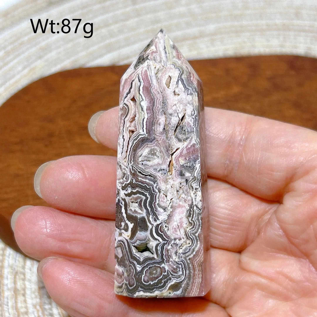 Polished Rhodochrosite tower point featuring beautiful rose pink and white banding for heart chakra healing and self-love.