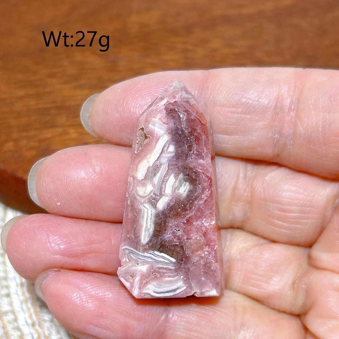 Polished 27g Rhodochrosite tower point featuring raspberry pink hues and white banding for heart chakra healing.