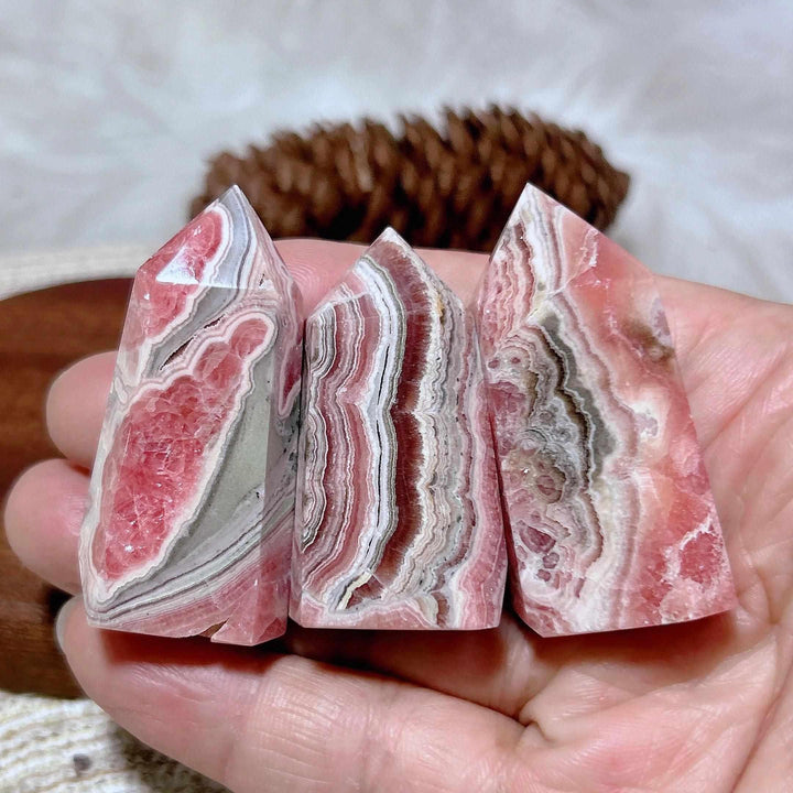Three polished Rhodochrosite tower points featuring vibrant rose-pink and white banding for heart chakra healing.