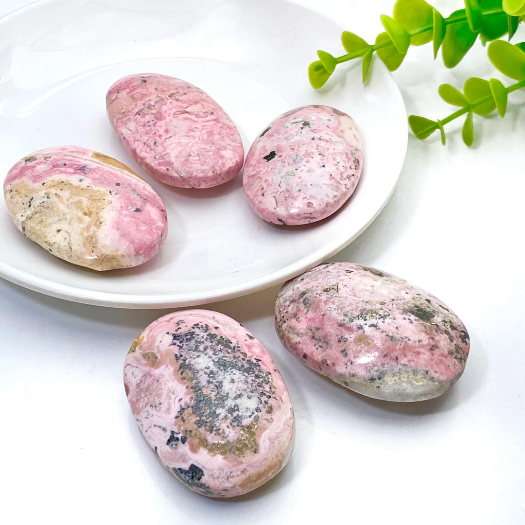 Polished natural pink Rhodonite palmstones with unique black mineral inclusions, perfect for healing and home decor.