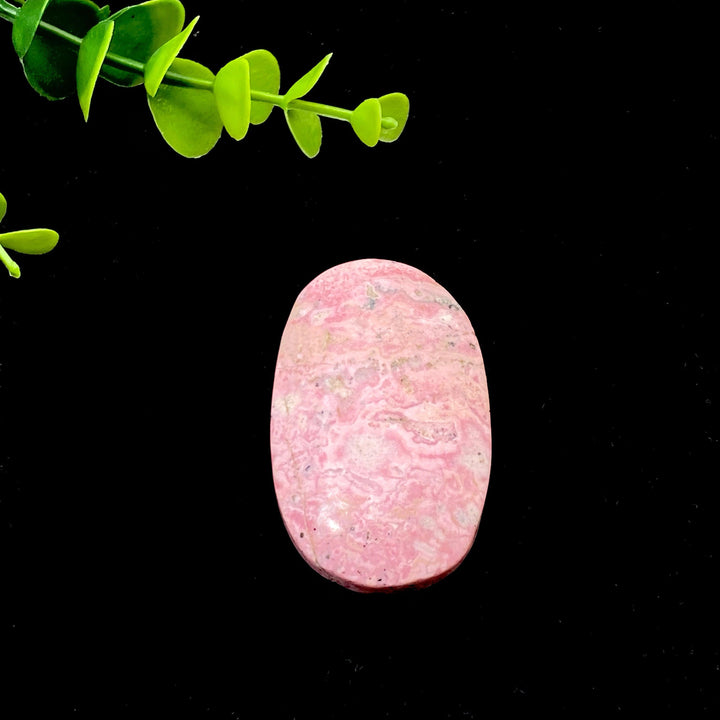 Polished natural pink Rhodonite palmstone with unique marbled patterns, perfect for healing, meditation, or home decor.