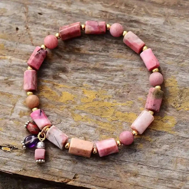 Rhodonite beaded stretch bracelet with pink rectangular and round gemstones, gold accents, and a small charm.