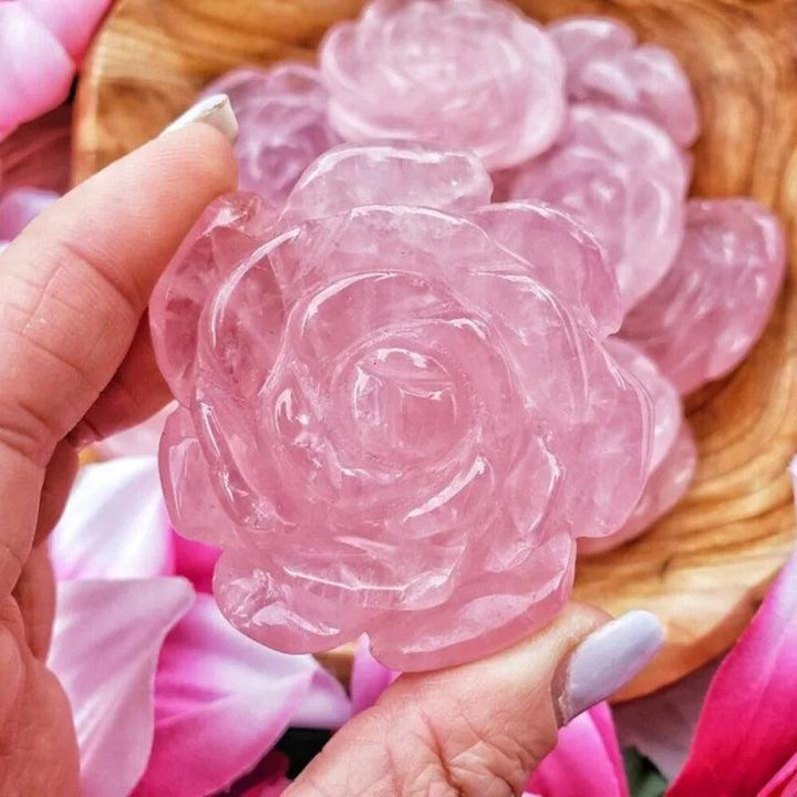 Hand holding a delicate pink Rose Quartz crystal carved peony flower sculpture, radiating love and tranquility.
