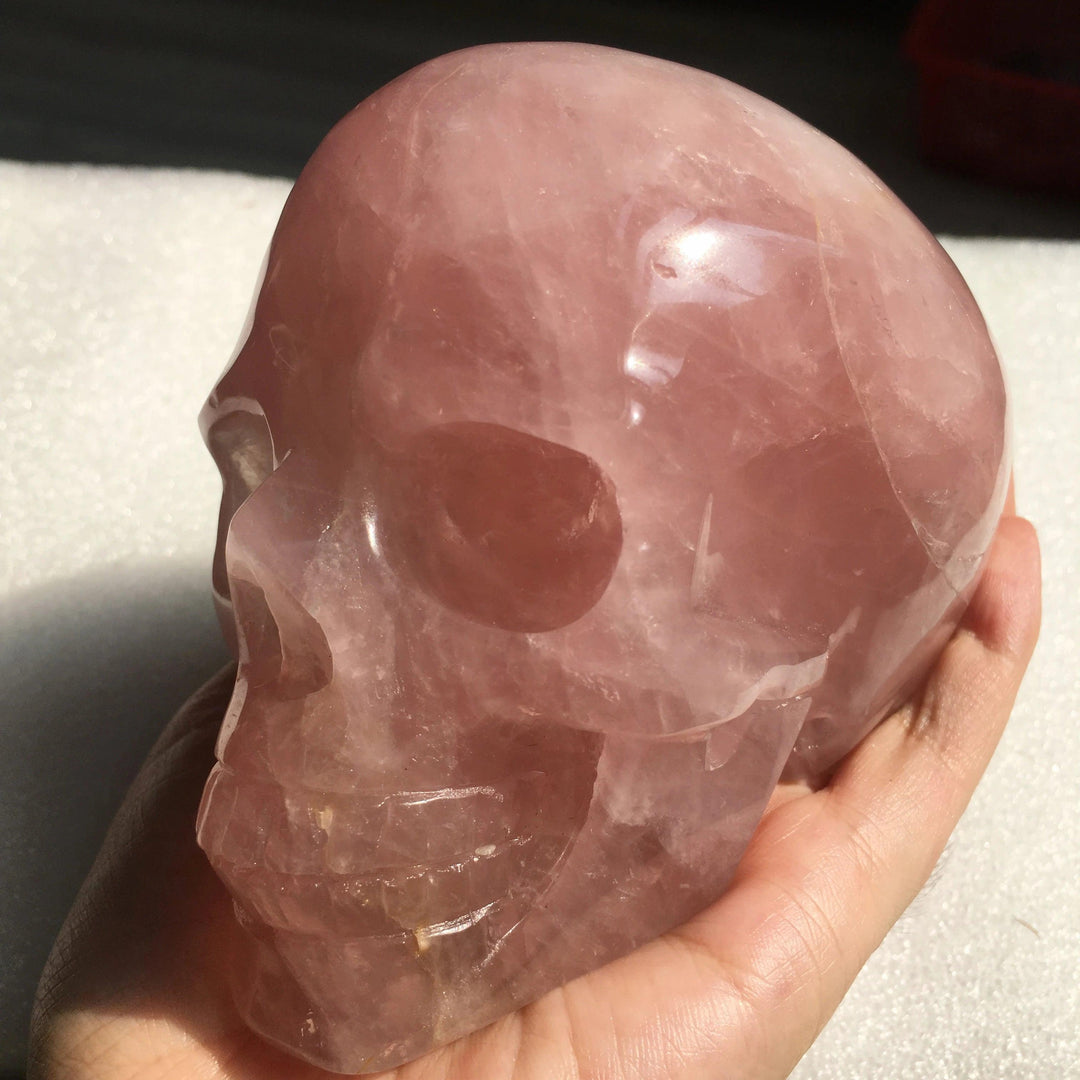 Hand-carved natural rose quartz crystal skull, a polished pink stone carving perfect for Reiki healing and home decor.