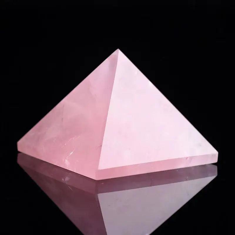 Polished natural rose quartz crystal pyramid, soft pink, for love and healing, reflected on a dark surface.