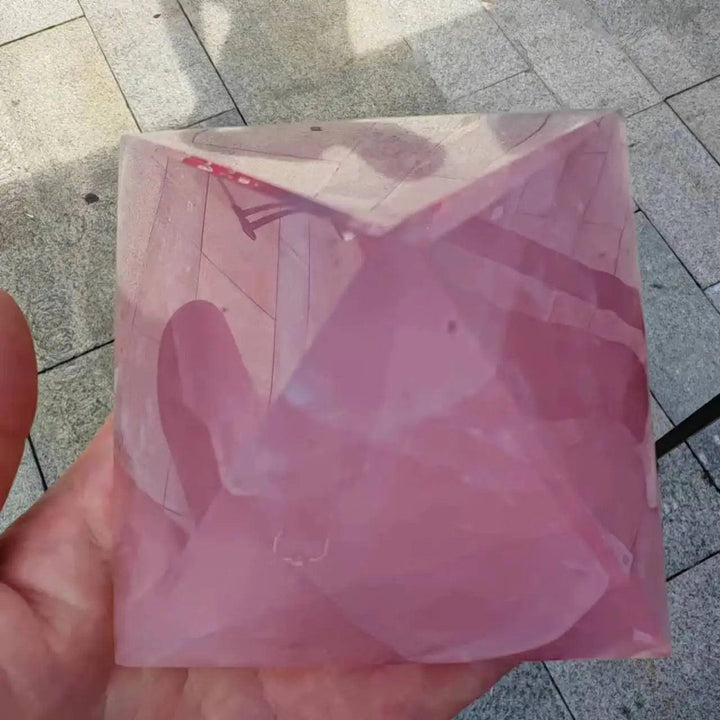 Polished rose quartz crystal pyramid, soft pink, held in a hand, showcasing its healing energy for love.