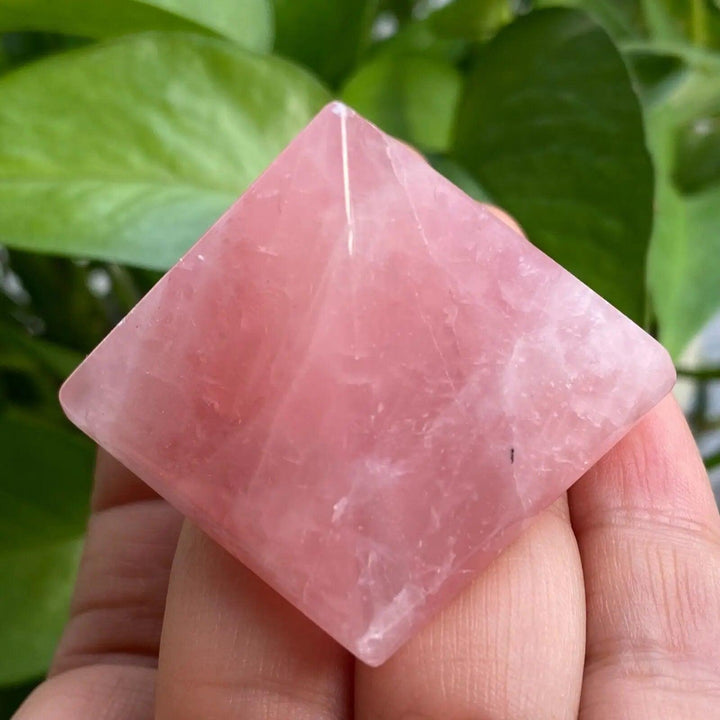 Polished natural Rose Quartz crystal pyramid in soft pink, held in a hand, promoting love and healing.