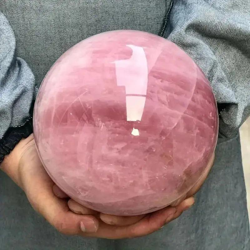 Polished Rose Quartz Crystal Sphere, a soft pink stone of unconditional love, held gently in hands.