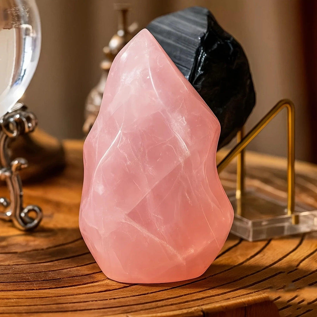 Polished Rose Quartz crystal torch tower with soft pink color, tapered upward, on a wooden surface.