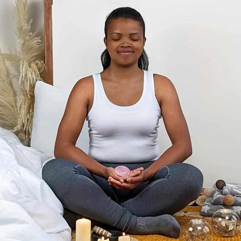 Woman meditating while holding a smooth, pale pink Rose Quartz palm stone for heart chakra healing and self-love.