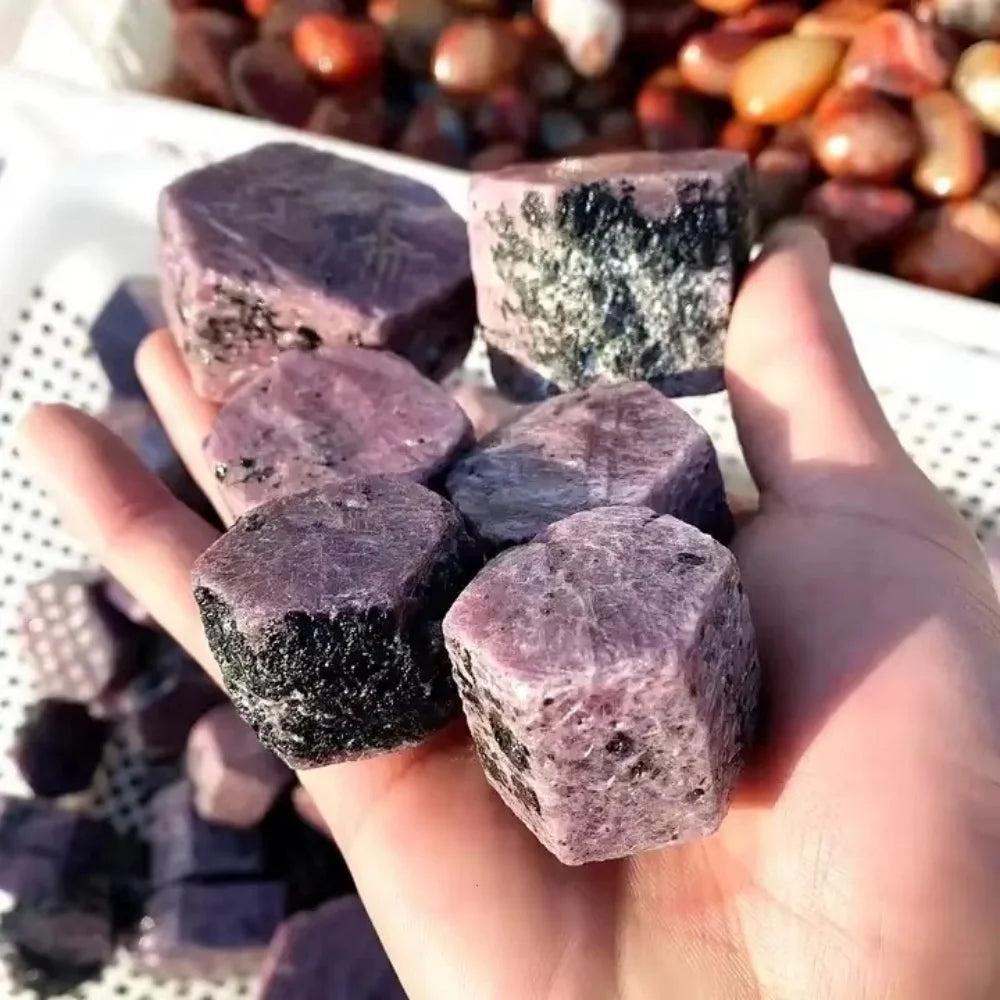 Hand holding deep red, rough Ruby Corundum raw crystals, showcasing natural hexagonal structure and inclusions for passion and courage.