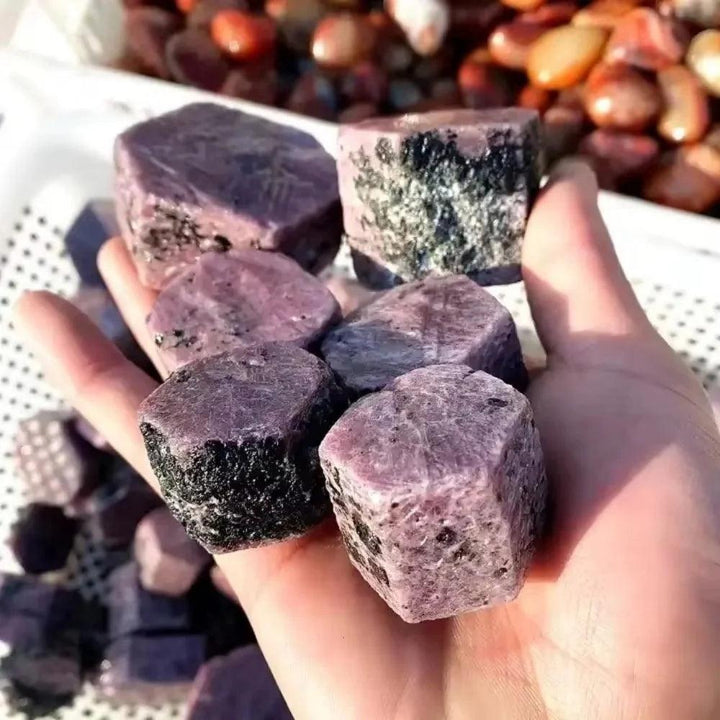Hand holding deep red, rough Ruby Corundum raw crystals, showcasing natural hexagonal structure and inclusions for passion and courage.