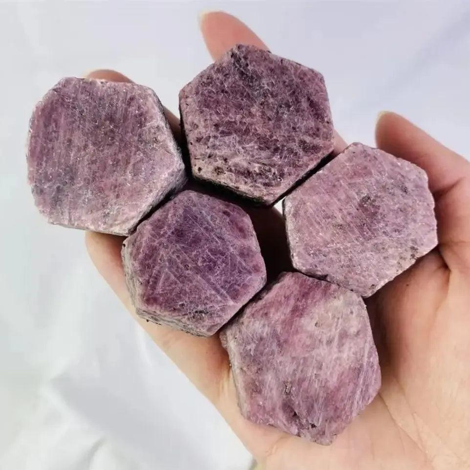 Hand holding five raw Ruby Corundum natural rough stone specimens, showcasing deep red color and hexagonal crystal faces.
