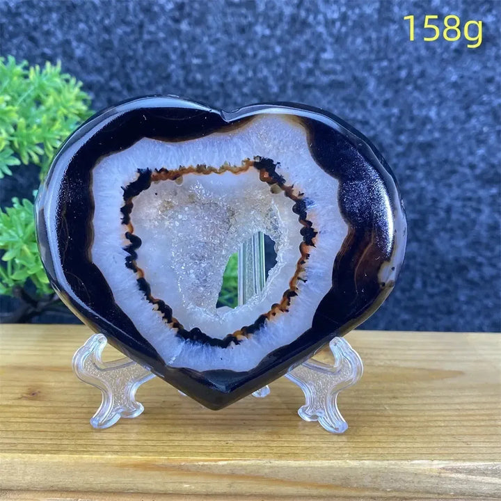Heart-shaped black agate geode with white and brown banding, sparkling crystal cave interior, 158g.