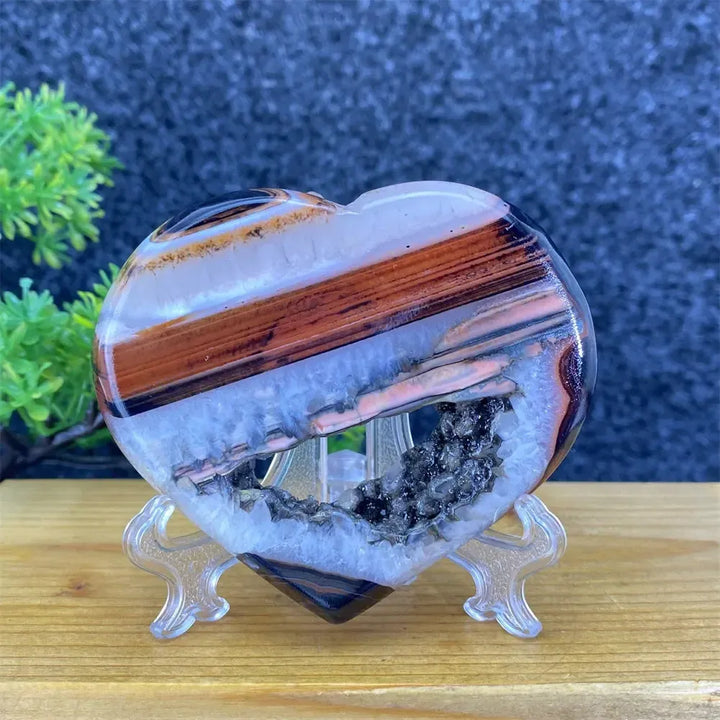 Heart-shaped black and red agate geode with white crystal cave, ideal for home decor and reiki.