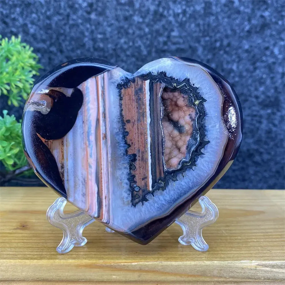 Heart-shaped black and red agate symbiont crystal geode with sparkling druzy, displayed on a stand.