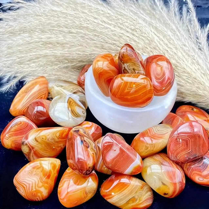 Polished sardonyx palm stones featuring vibrant reddish-brown, honey, and white bands for grounding and strength.