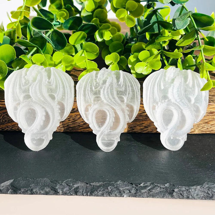 Three luminous selenite carved flying dragons, showcasing their milky luminescence and ancient intention.