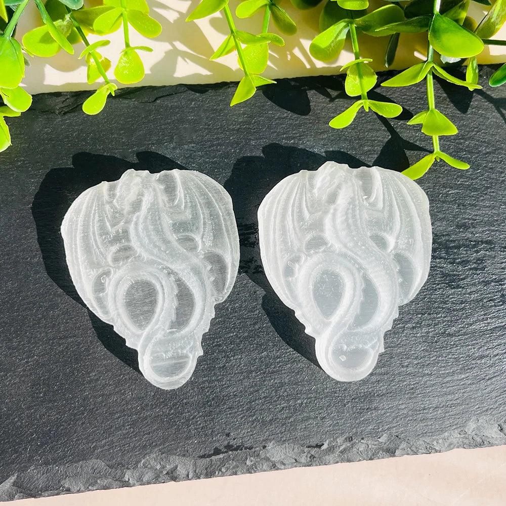 Two luminous selenite crystal carved flying dragons, showcasing their milky luminescence and intricate details.