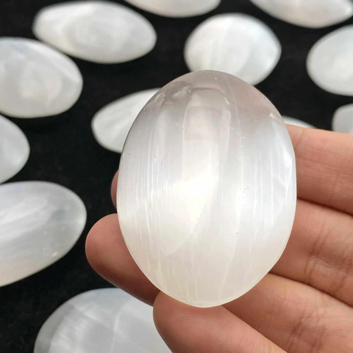 Smooth, translucent white natural selenite palm stone for healing, meditation, and elegant home decor.