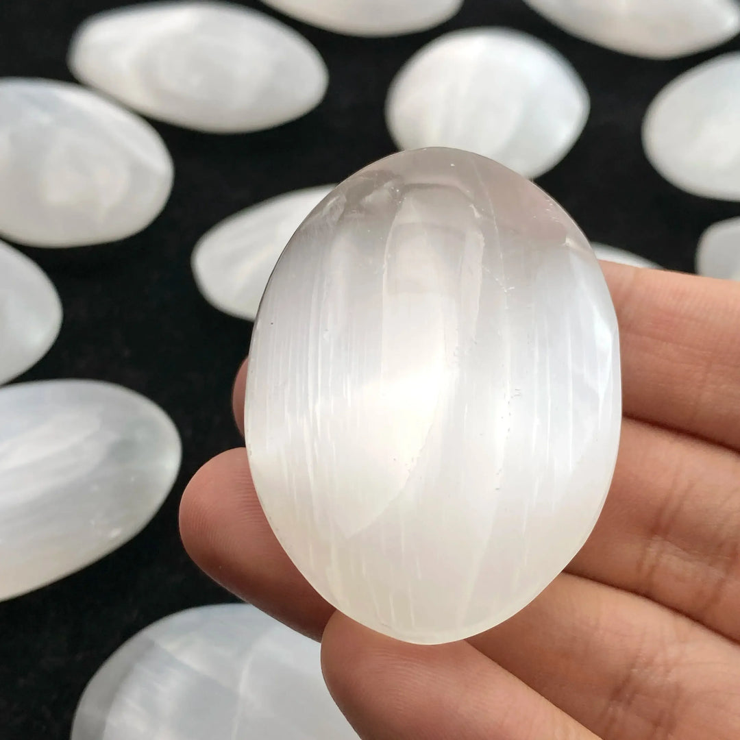 Smooth, translucent white natural selenite palm stone for healing, meditation, and elegant home decor.