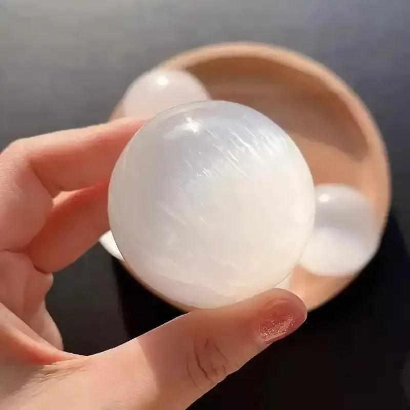 Polished white Selenite crystal sphere with a silky, glowing sheen for peaceful energy and Crown Chakra cleansing.